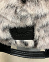 Close-up of a faux fur product with a brand logo on a neutral background
