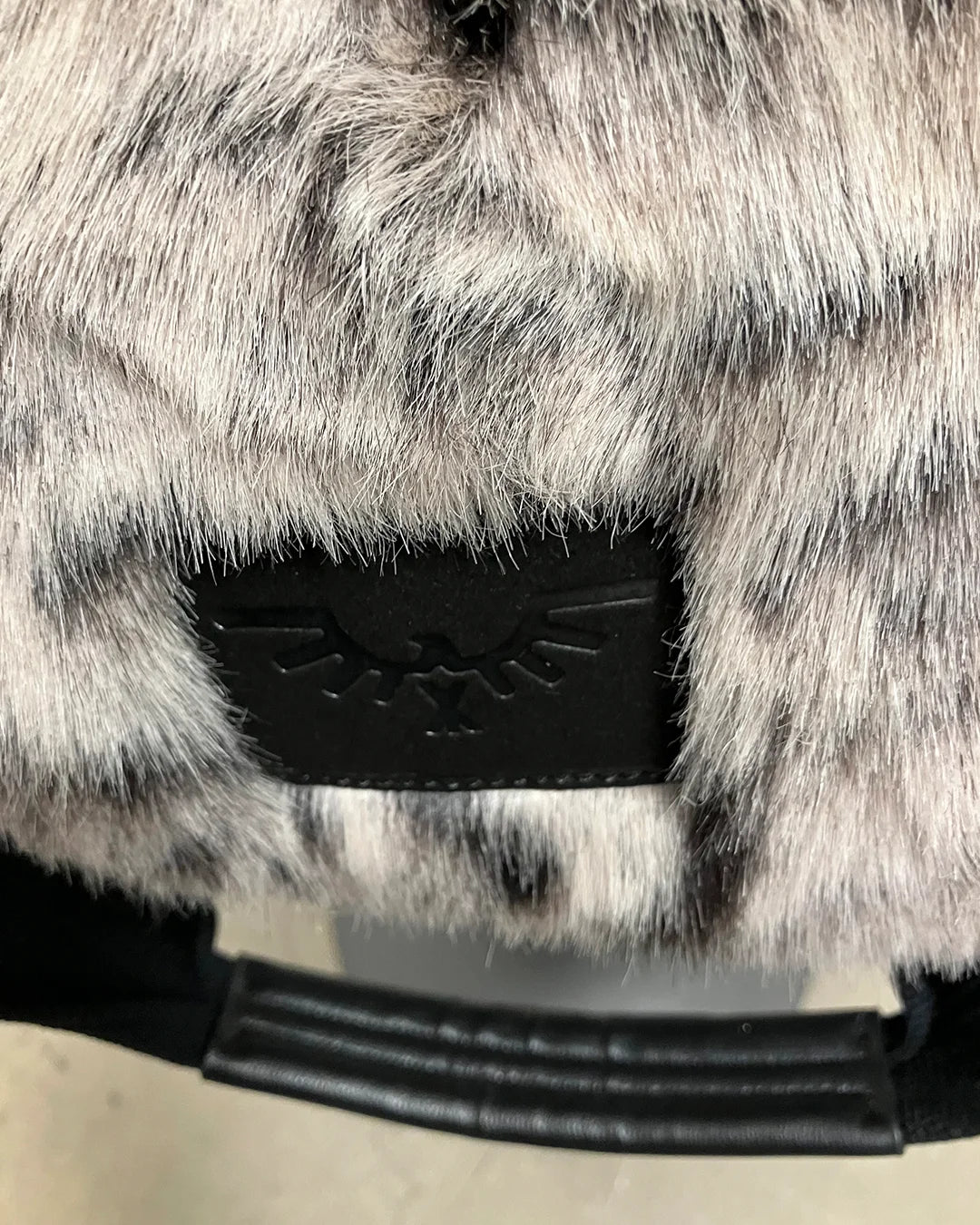 Close-up of a faux fur product with a brand logo on a neutral background