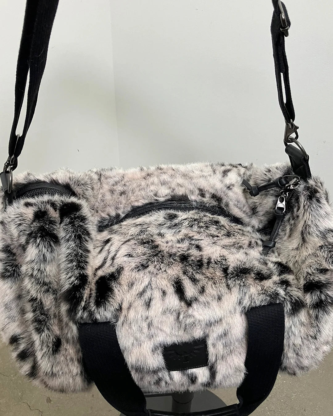 faux fur duffle bag with black straps on a neutral background