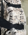 Close-up of a fake fur weekender duffle bag with a black strap on a neutral background