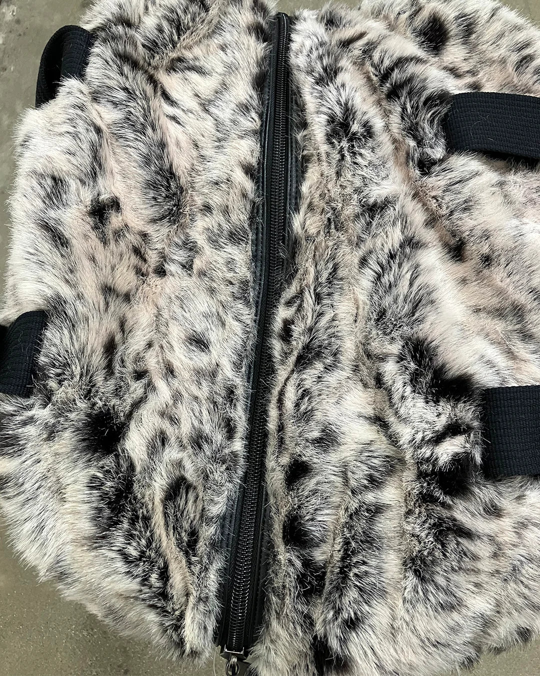 Close-up of a fake fur weekender bag with a zipper on a neutral background