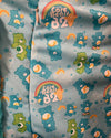 Fabric with Care Bears pattern featuring blue and green bears, rainbows, and 'Care Bears 82' text on a gray background.