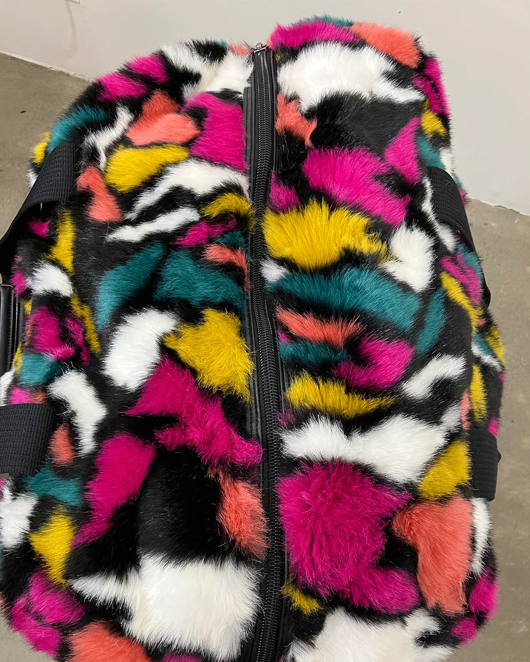 Multicolored fuzzy weekender duffle bag with a multicolor rainbow faux fur on a neutral background