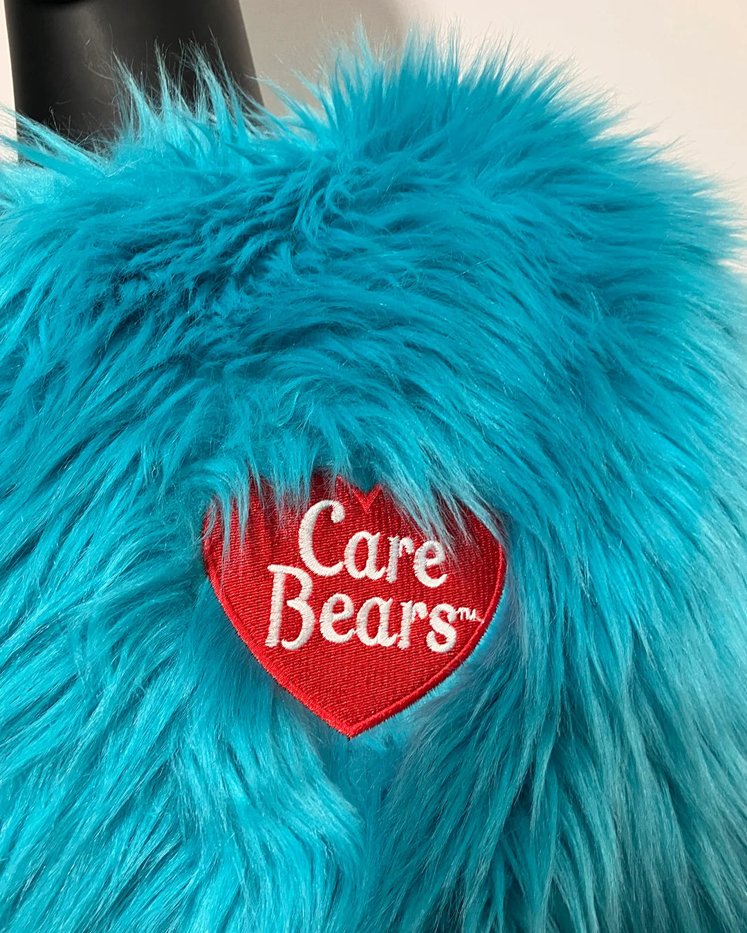Turquoise fluffy fabric with a red 'Care Bears' patch