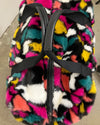 Multicolored fuzzy fake fur weekender bag with a black strap on a neutral background