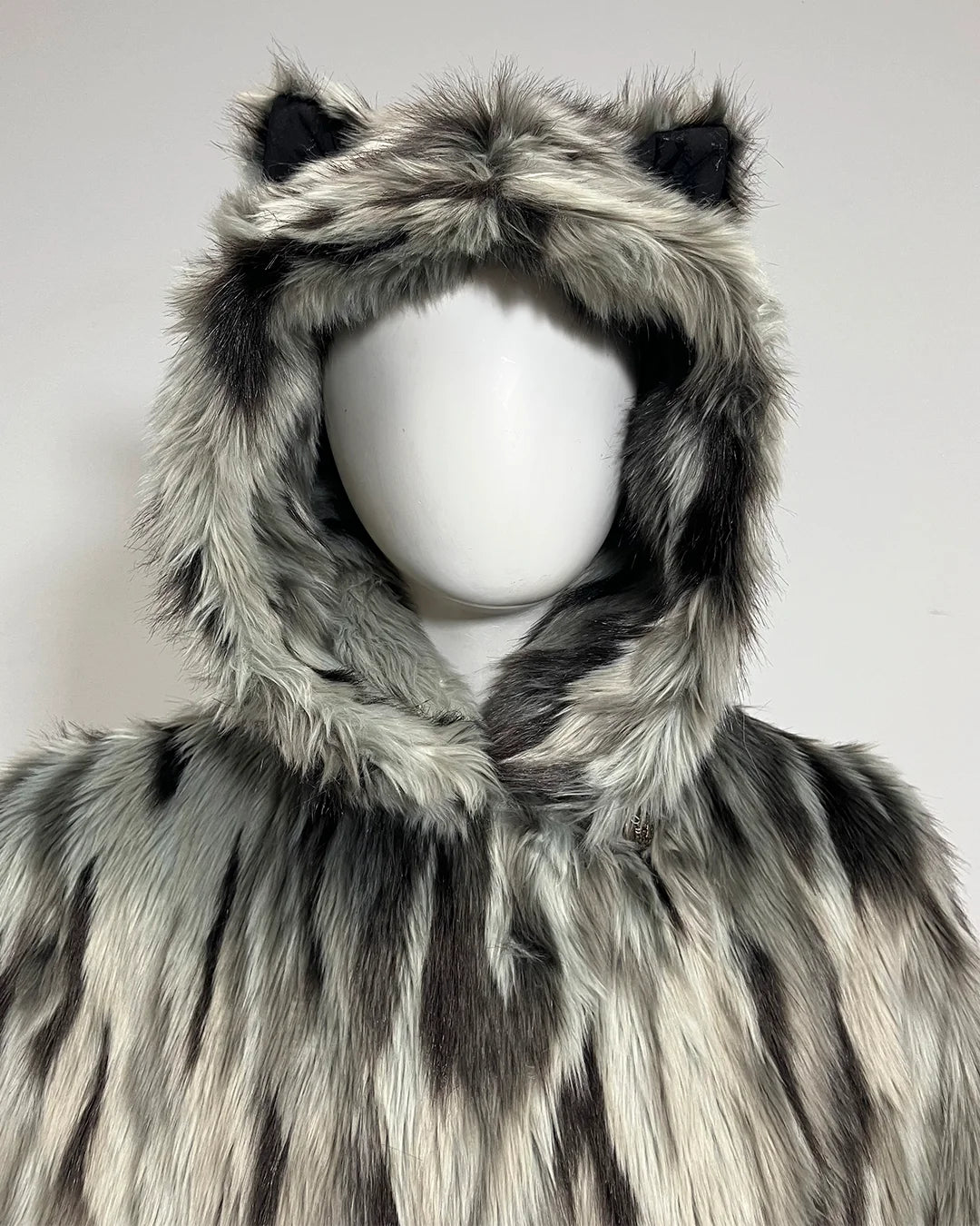 A hooded faux fur coat with animal-ear hood details, displayed on a white mannequin against a plain light gray background.