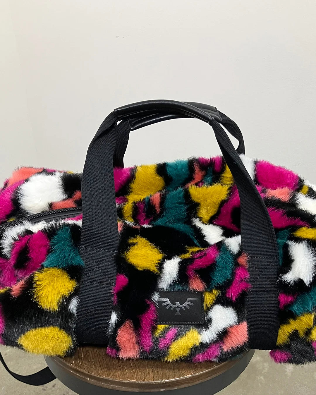 Multicolored fluffy bag with a visible brand logo on a neutral background