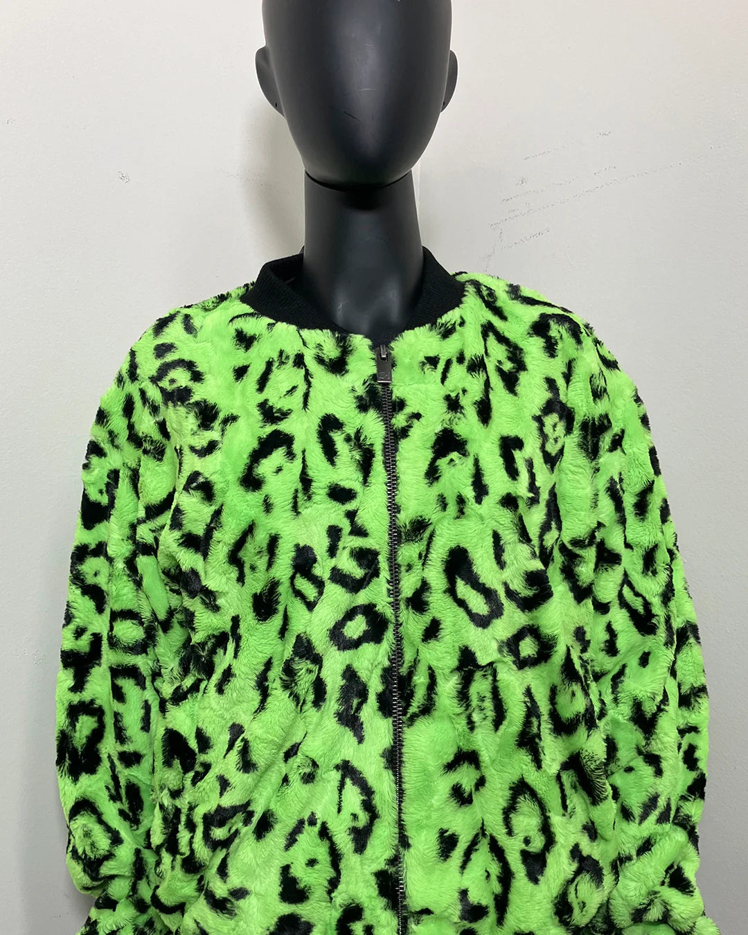 Mannequin wearing a neon green jacket with black leopard print pattern on a white background