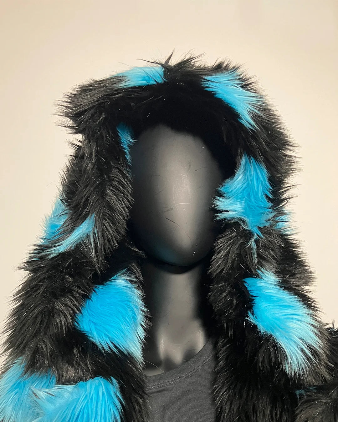 Mannequin wearing a black and blue fur-lined hood against a beige background