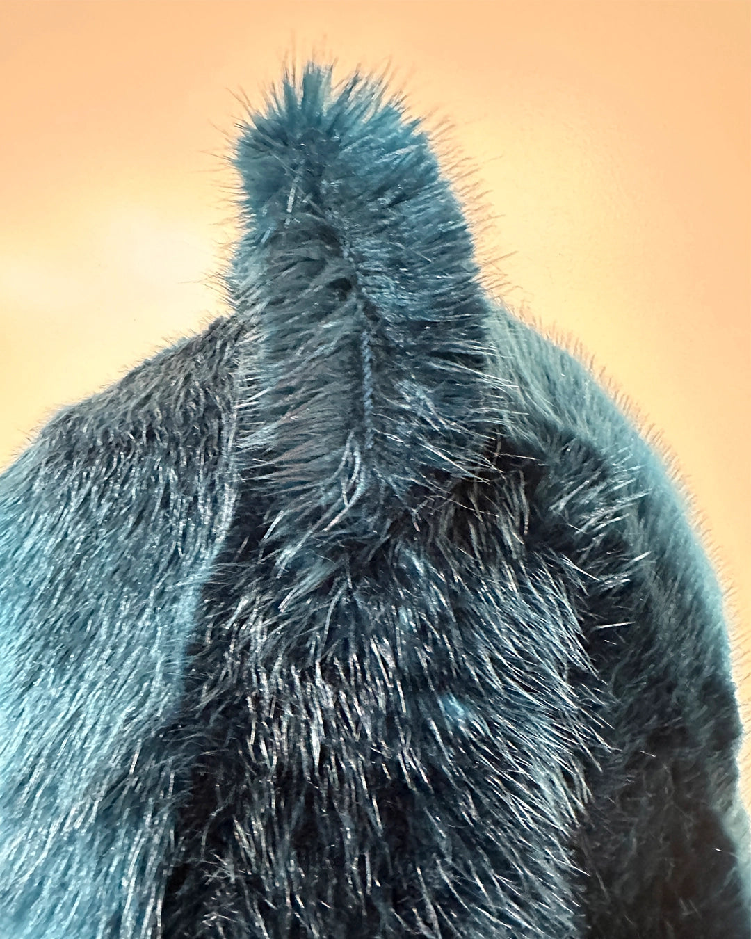 Close-up of a blue green fur side profile of  a hood with ears
