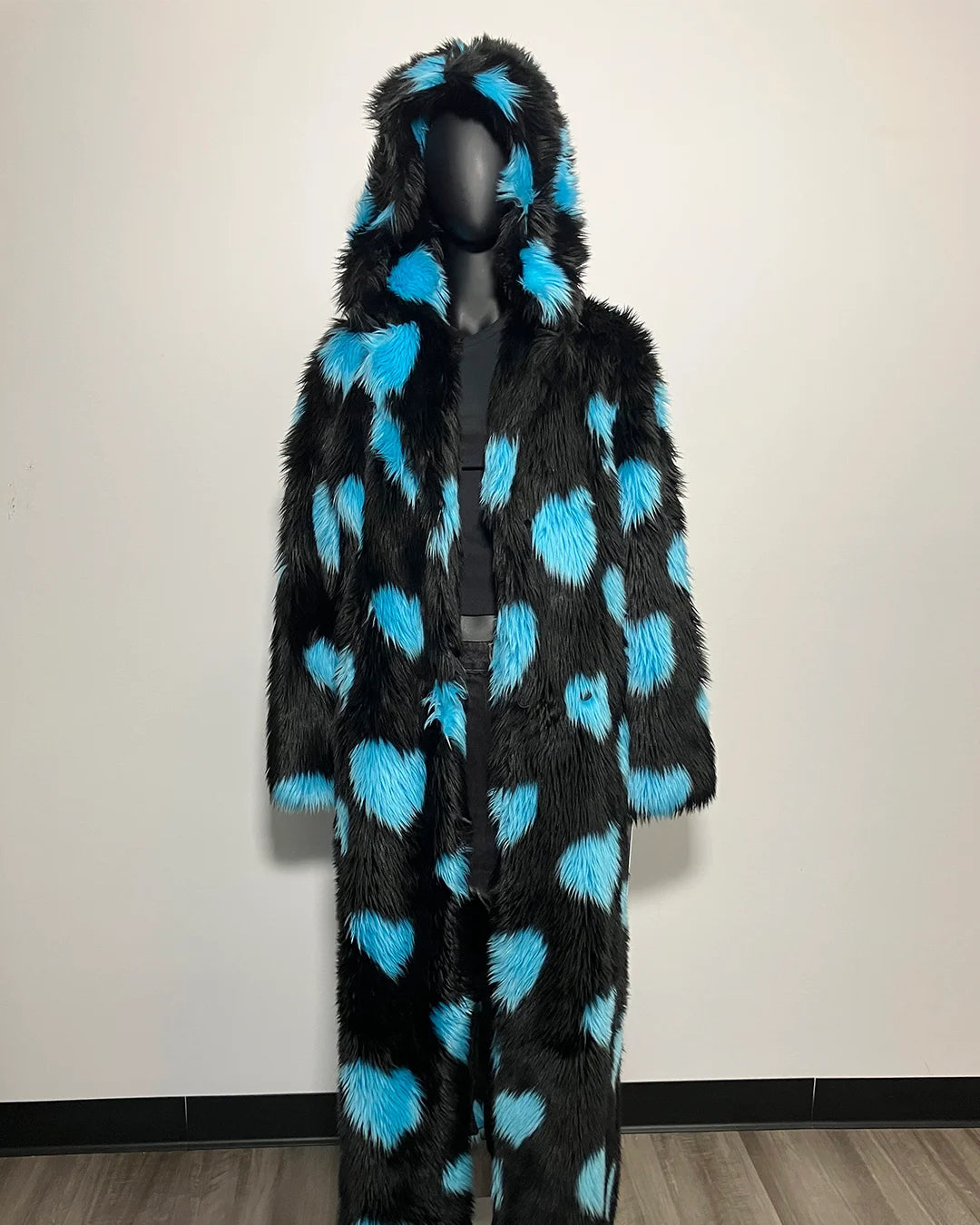 Black fur coat with blue heart patterns on a mannequin against a plain background