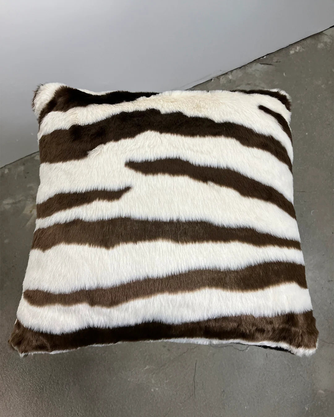 brown zebra with brown and white faux fur pattern on a gray floor.