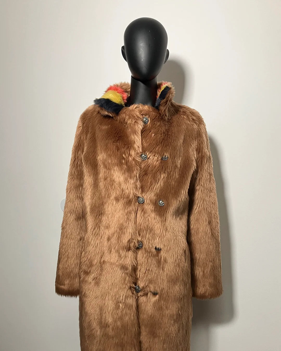 Brown faux fur coat on a mannequin against a plain background