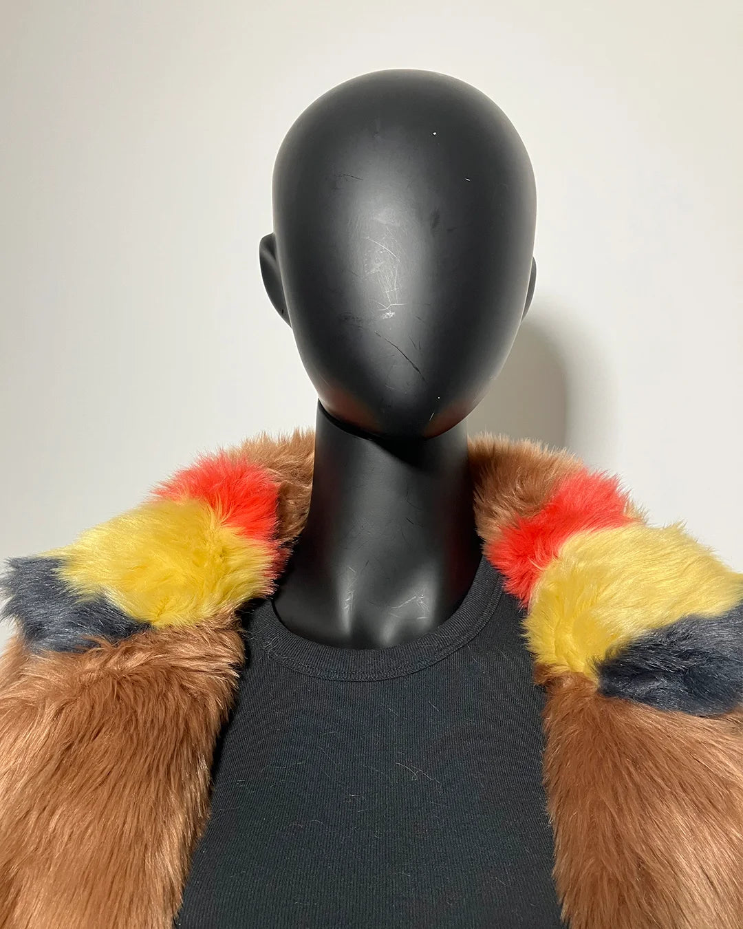Mannequin wearing a colorful faux fur coat with a plain background