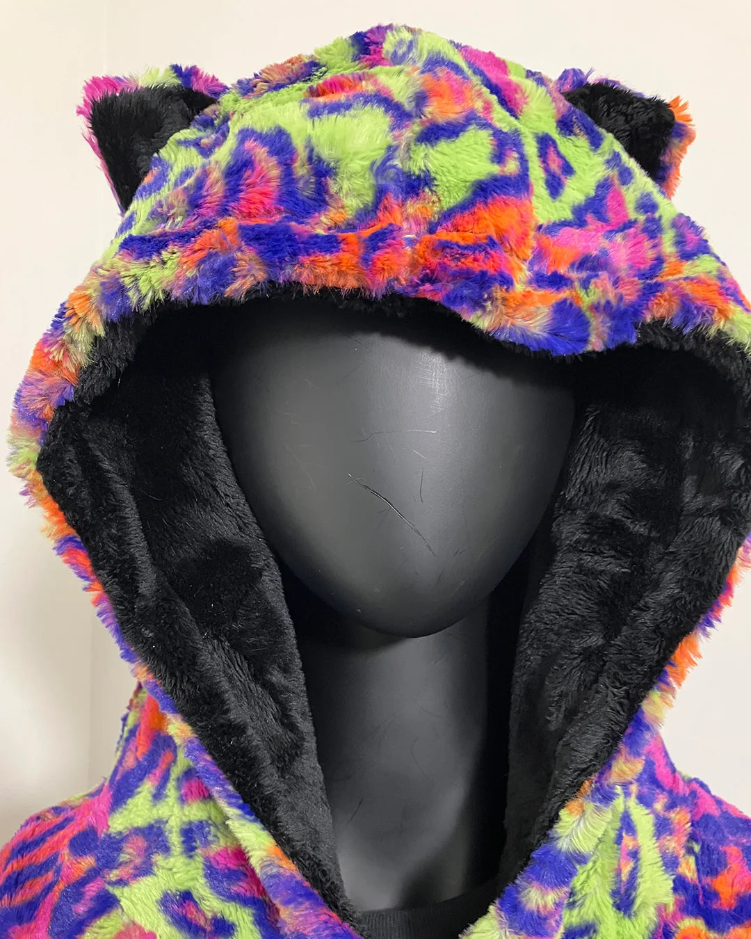 Mannequin head wearing a colorful neon leopard print tie-dye inspired hoodie with black lining.