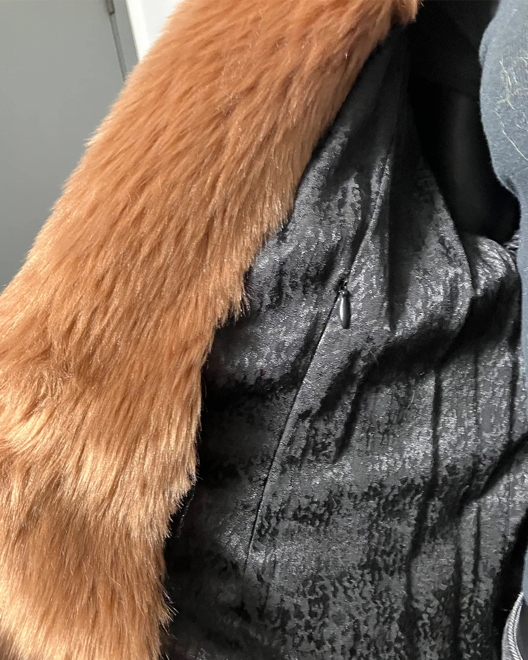 Close-up of a textured fabric with a faux fur trim on a neutral background