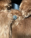 Close-up of a fluffy brown garment with a decorative button.