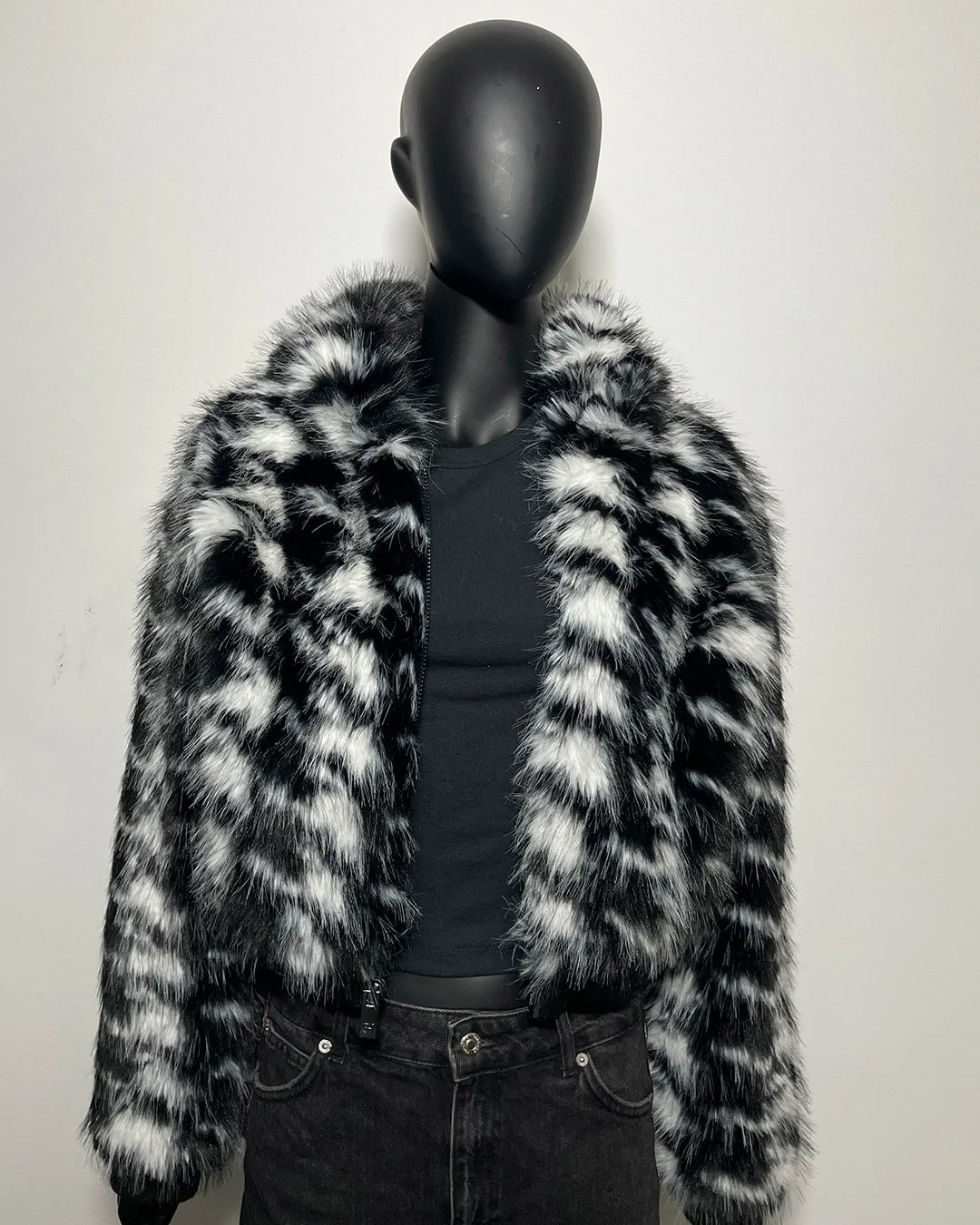 Mannequin wearing a black and white fake fur coat against a plain background