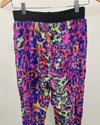 Colorful neon leopard print pants on a hanger against a white background