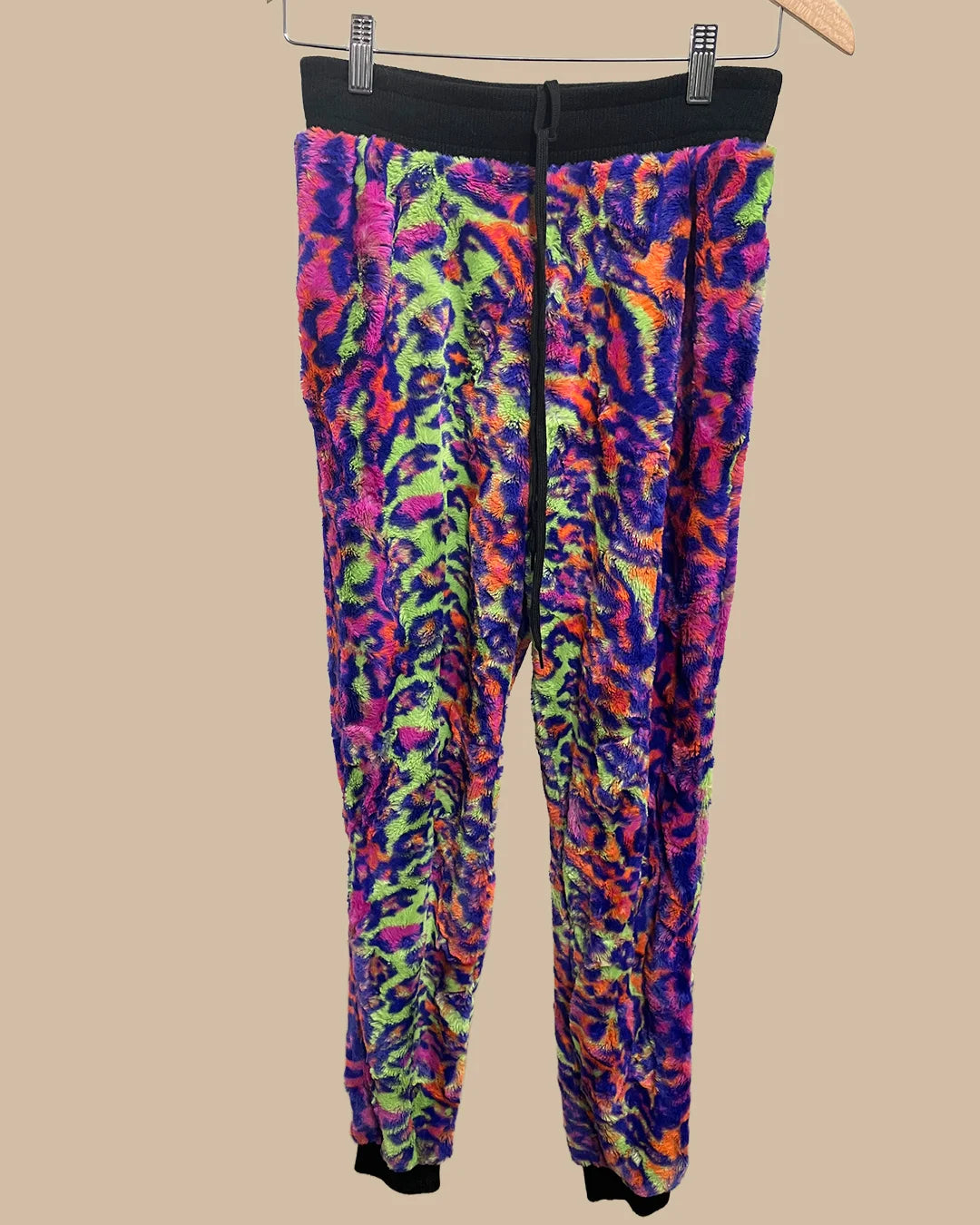 Colorful tie-dye neon leopard print jogger pants on a beige background