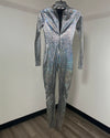 A long-sleeve, full-length metallic iridescent silver jumpsuit with a textured, reptile-like scale pattern, hanging on a black hanger against a plain indoor wall.