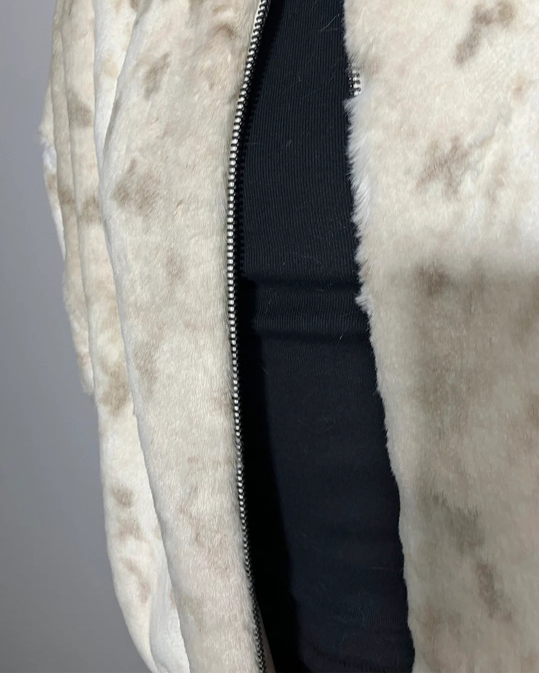 Close-up of a beige fur coat with a zipper on a gray background