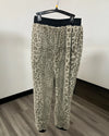 Leopard print fleece pants hanging on a black hanger against a plain wall and wood floor.