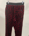 Red and black leopard print pants on a hanger against a white background