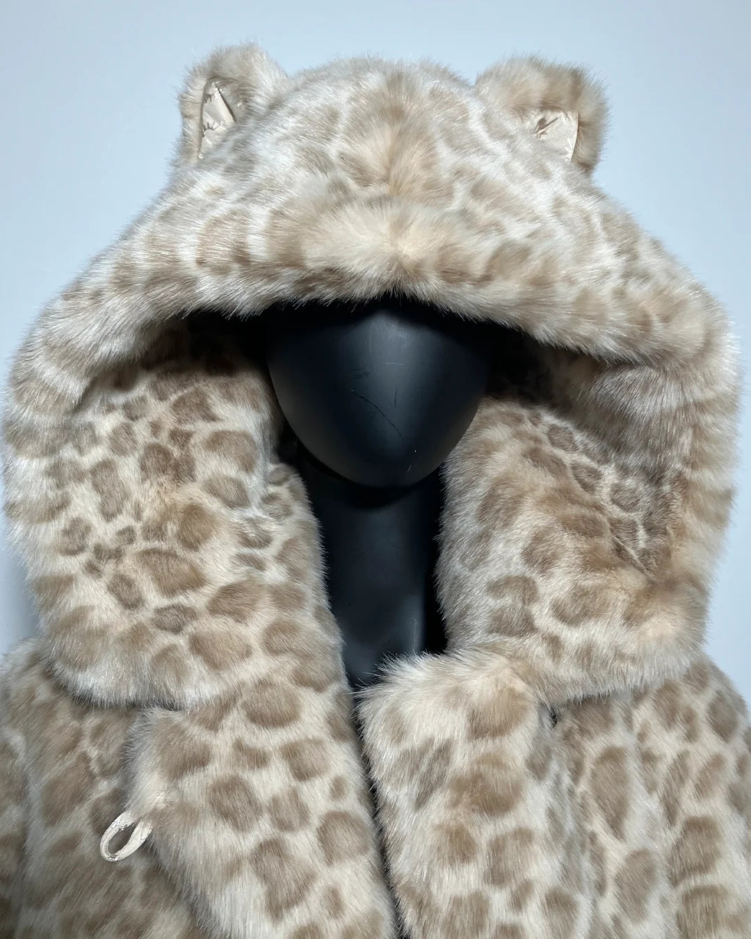 Leopard print fur coat on a mannequin against a light blue background
