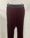 Red and black leopard print pants on a hanger against a beige background