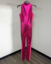 A sleeveless, high-neck, full-length jumpsuit in a metallic hot pink color with a subtle textured pattern, hanging on a black hanger against a plain white wall.