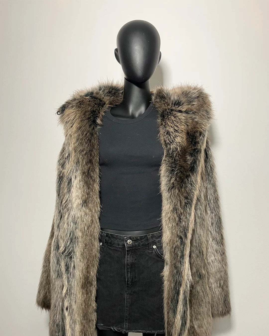 Mannequin wearing a fake fur coat and black outfit against a plain background
