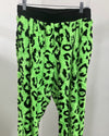 Neon green leopard print pants on a hanger against a white background
