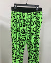 Neon green pants with black leopard print pattern on a hanger against a white background