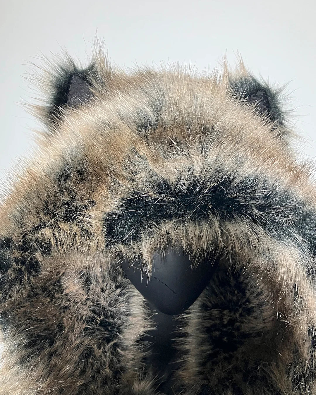 Close-up of a fluffy, grey, brown and black faux fur coat with an oversized hood and wolf ears
