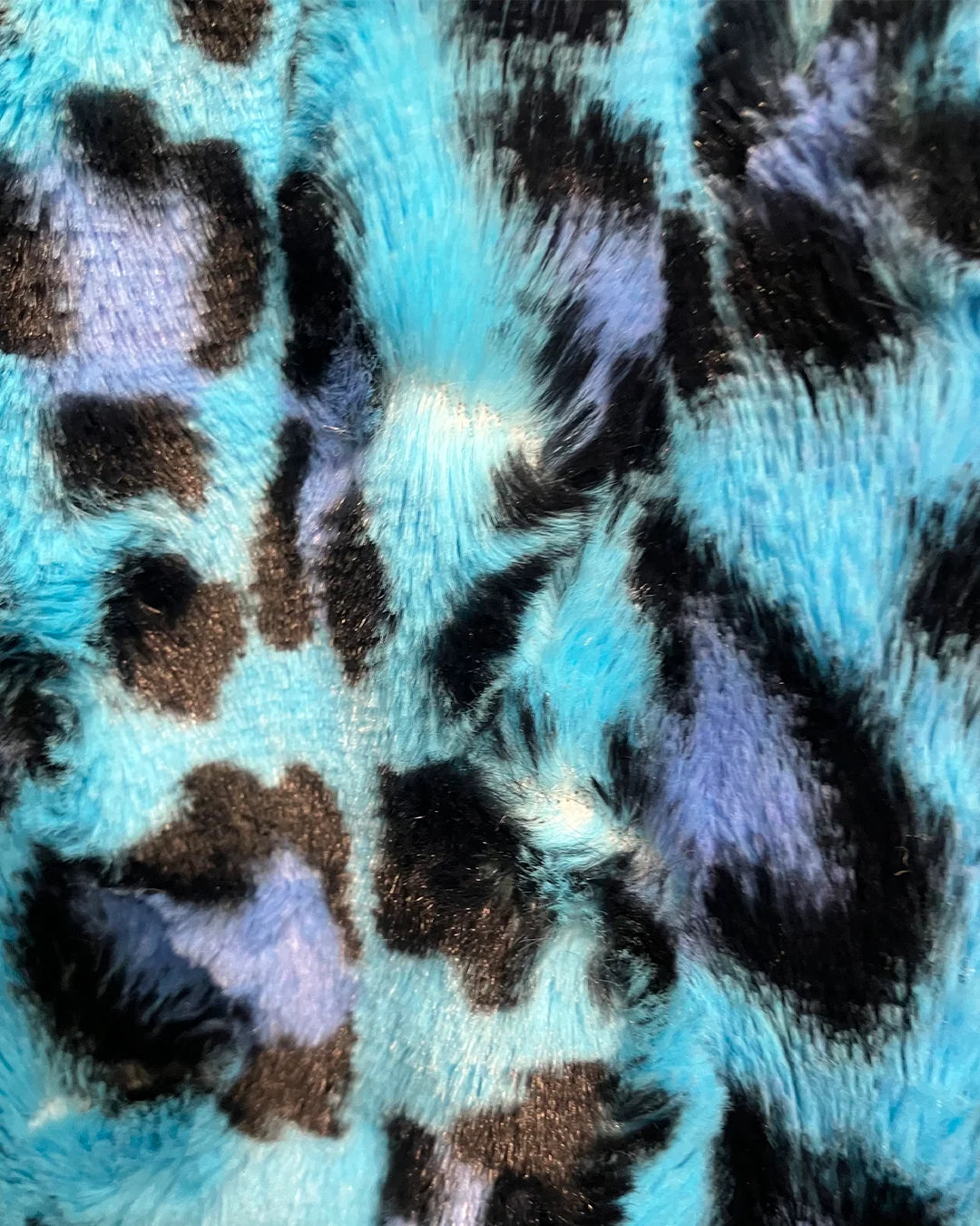 Close-up of a fabric with blue, black, purple leopard print pattern
