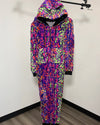 A neon multicolor animal-print hooded jumpsuit or onesie hanging on a black clothing rack against a plain white wall with a wood-look floor.