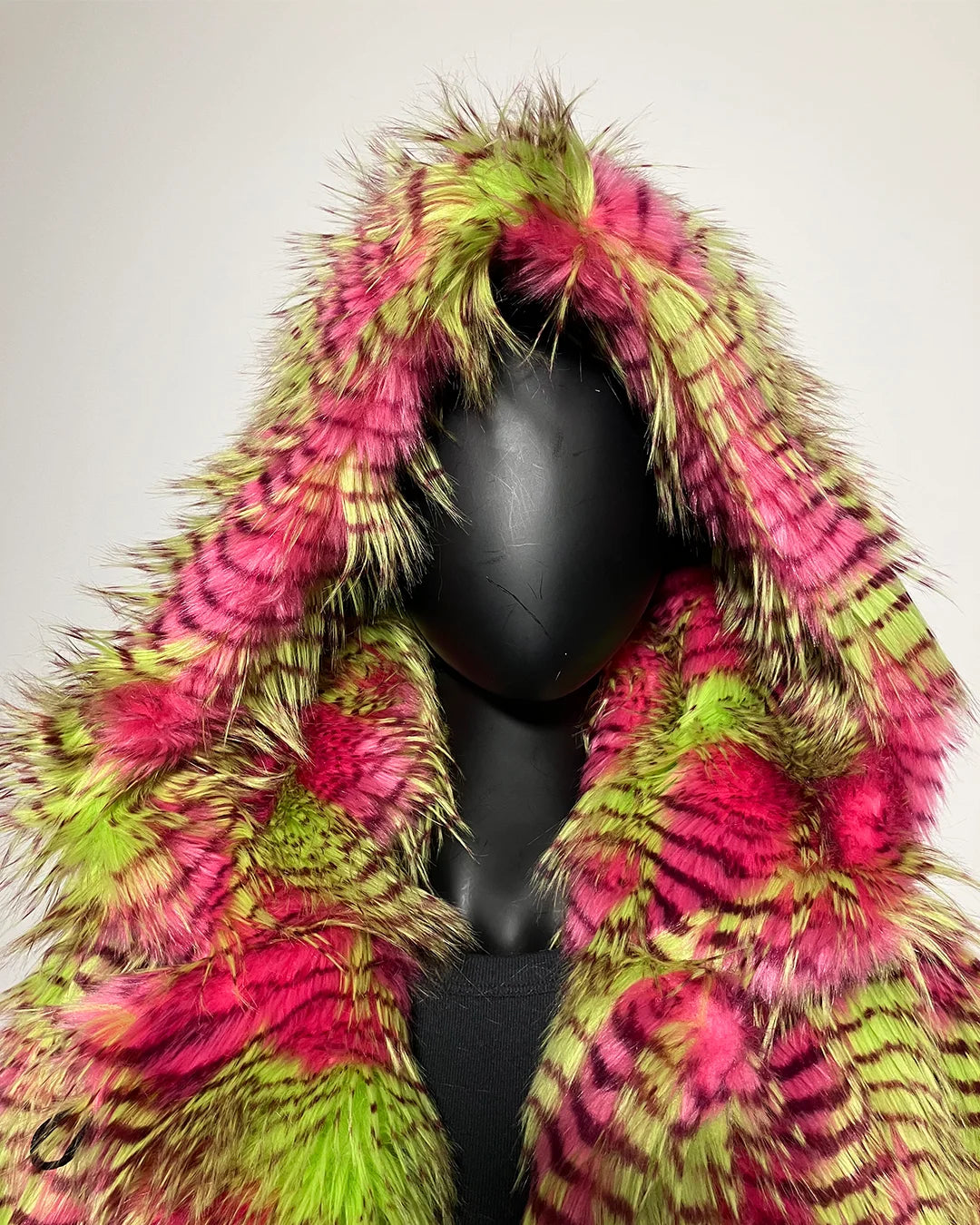 Mannequin wearing a colorful feathered coat with pink and green patterns on a plain background