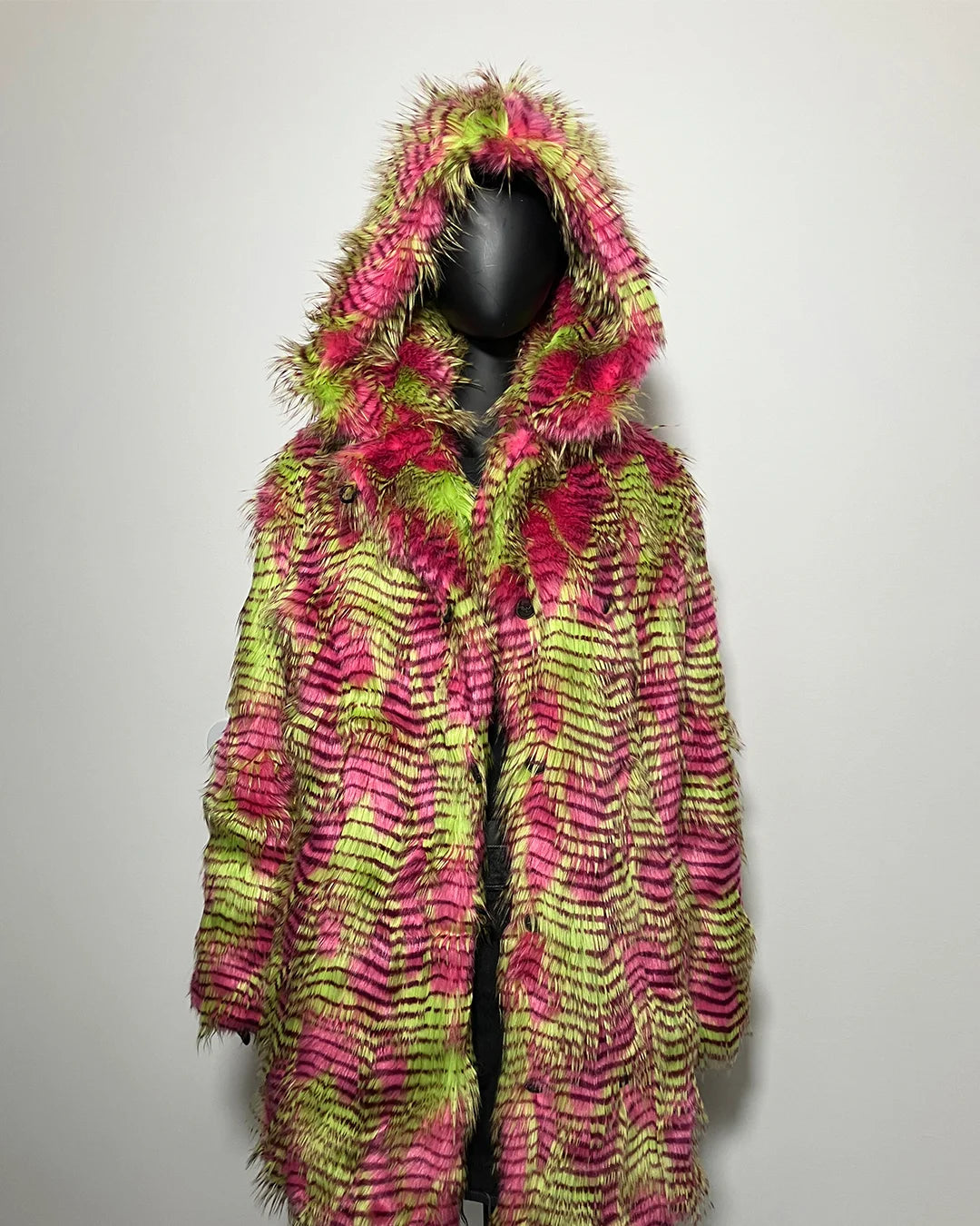 Colorful hooded coat with pink and green pattern on a mannequin against a plain background