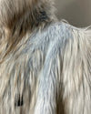 Close-up of a mannequin wearing a long pile, light-colored faux fur coat against a neutral background