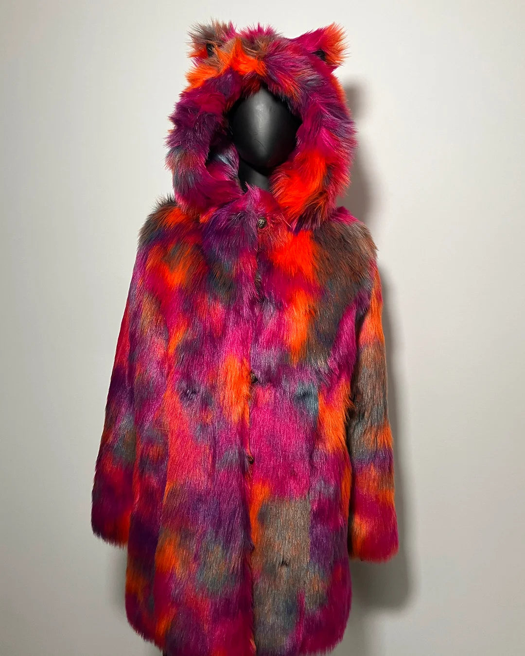 Multicolored faux fur coat with hood on a mannequin against a plain background