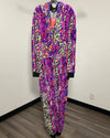 A zip-up hooded onesie featuring a vibrant multicolor abstract pattern in purple, pink, orange, and green. The onesie is displayed on a hanger against a plain white wall with a wood-look floor.