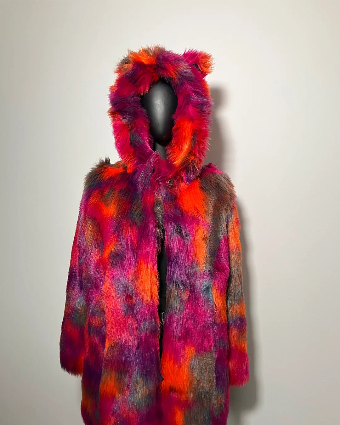 Multicolored fur coat with hood on a mannequin against a plain background