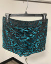 A pair of women's shorts with a black and teal abstract tiger print pattern, hanging on a black hanger.