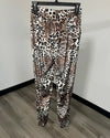 Leopard print ankle-length leggings hanging on a black hanger against a plain wall and wood-look floor.