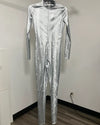 A full-body metallic silver jumpsuit with a textured, crinkled pattern, hanging on a black hanger against a plain white wall.