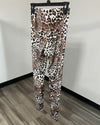 Leopard print leggings hanging on a black hanger against a white wall and wood-look floor.