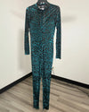 A long-sleeve, full-length jumpsuit with a mock neck, featuring an abstract black and teal tiger print pattern, displayed on a hanger against a plain wall.
