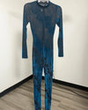 A long-sleeve, full-length jumpsuit with a blue and black snakeskin pattern, displayed on a hanger against a plain indoor wall.
