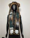 A hooded scarf displayed on a black mannequin against a plain light background. The scarf has a Southwestern geometric pattern in green, brown, beige, and gray, with brown faux-fur trim, bear ears on the hood, and white paw prints near the bottom.